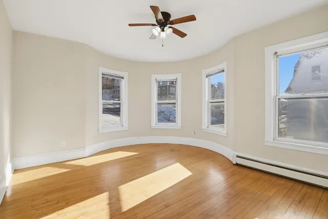 a view of empty room with wooden floor and fan