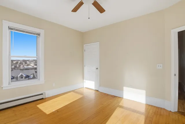 a view of an empty room with window and wooden floor