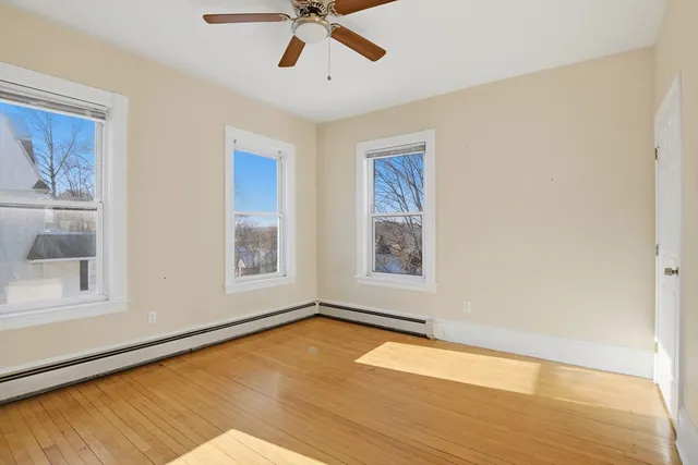 a view of empty room with wooden floor and fan
