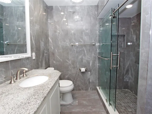 a bathroom with a granite countertop sink a toilet and shower