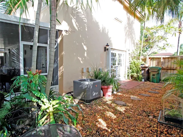 a backyard of a house with potted plants and palm tree
