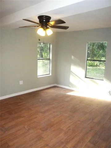en empty room with windows and chandelier fan