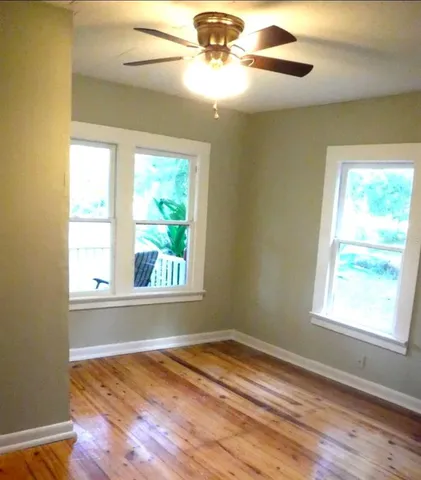 a view of empty room with wooden floor and fan