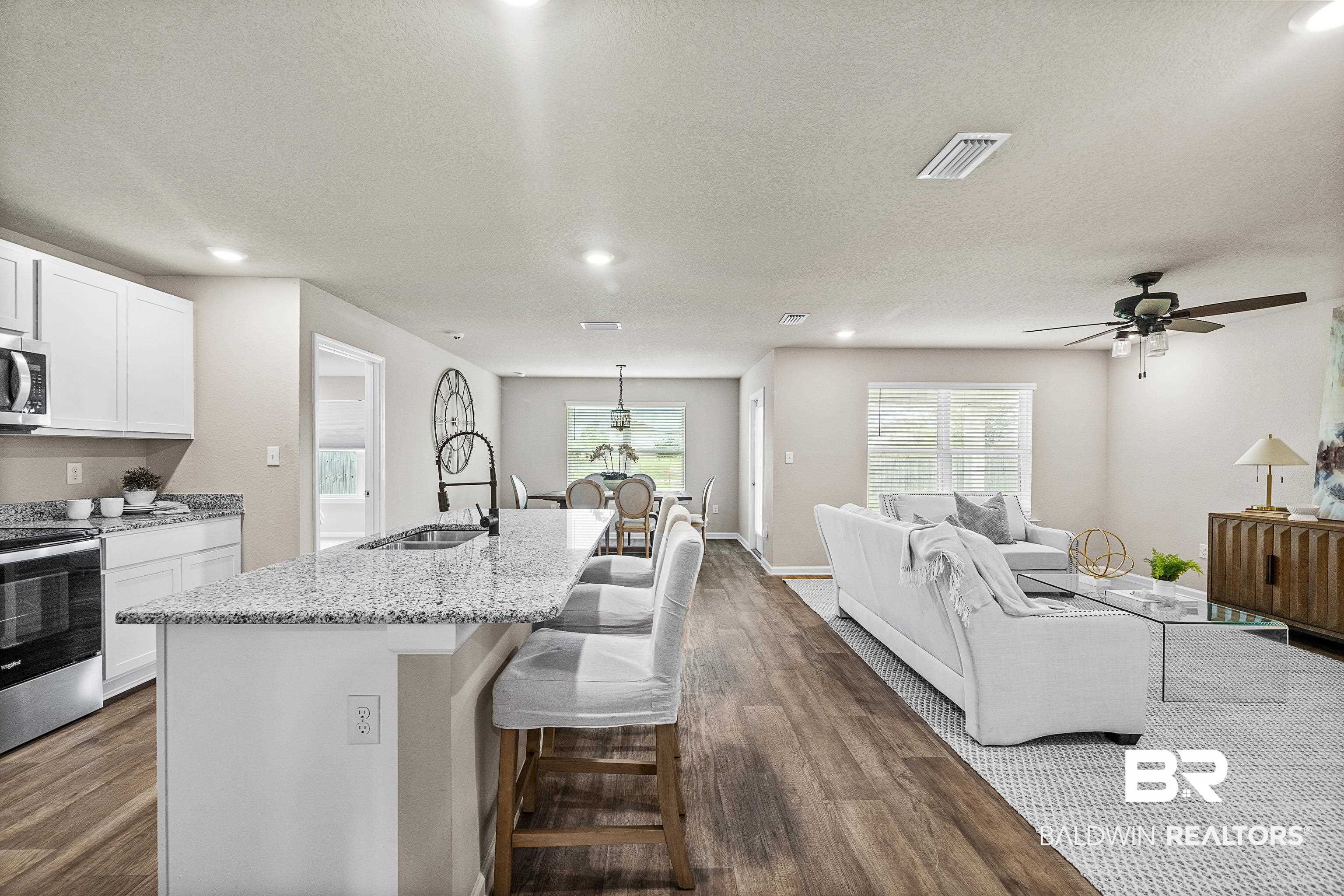 23916 Avernus Loop Daphne, AL 36526 - Photo 2 of 30 Kitchen with a kitchen bar, a textured ceiling, white cabinetry, dark wood-type flooring, and stainless steel appliances