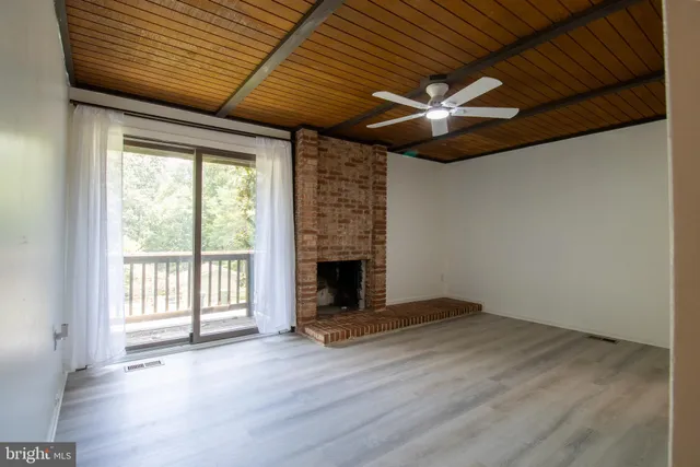 a view of an empty room with wooden floor fireplace and a window