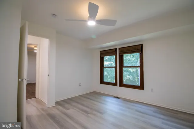 an empty room with wooden floor chandelier and glass door