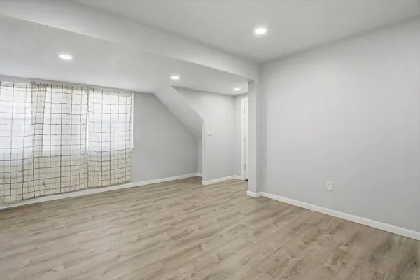 an empty room with wooden floor and fan