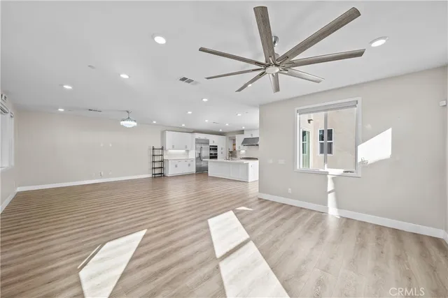 a view of an empty room with a window and kitchen view