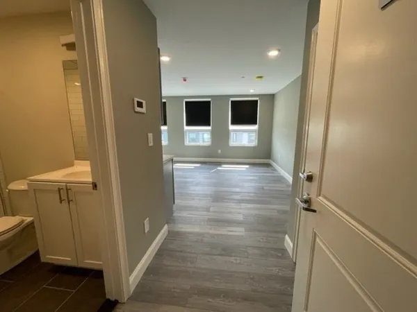 a view of a hallway with wooden floor and a bathroom