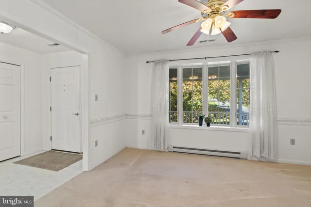 an empty room with a window and a chandelier fan