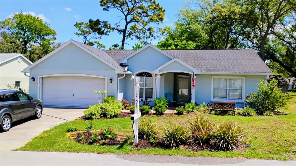 a front view of a house with a yard and a garden
