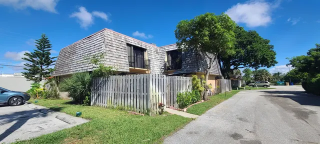 a view of a house with a small yard plants and a large tree