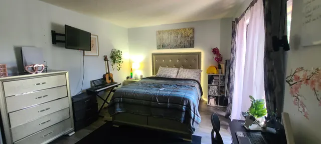 a bedroom with a bed and a flat tv screen on the dresser