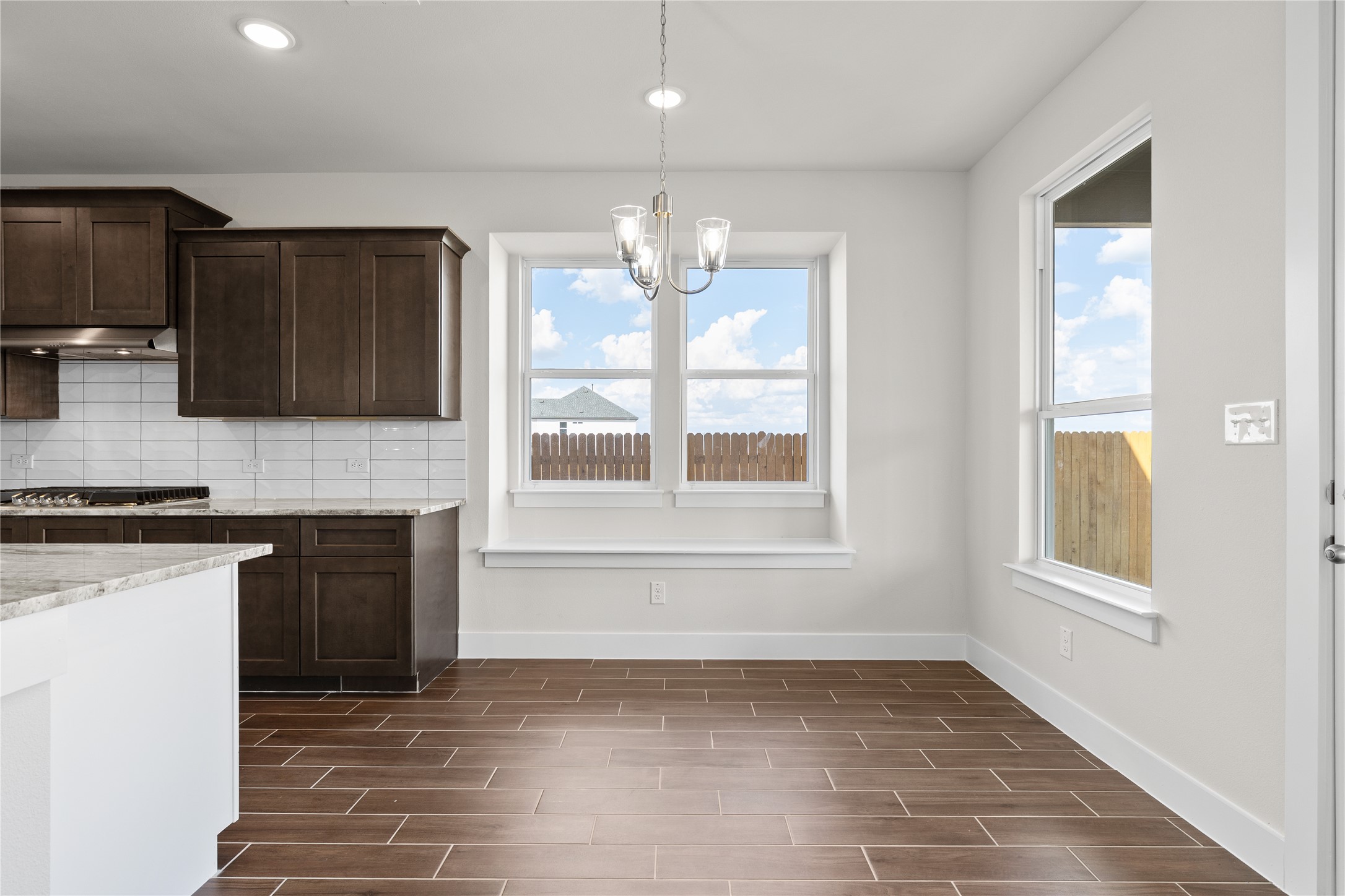 19705 Domino Champ Road Pflugerville, TX 78660 - Photo 18 of 38 Rich wood-look tile flooring and a built-in window seat enhance this bright dining space.