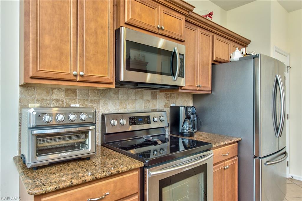 12859 Carrington Circle, Unit 3202 Naples, FL 34105 - Photo 5 of 28 a kitchen with stainless steel appliances granite countertop a stove microwave and refrigerator