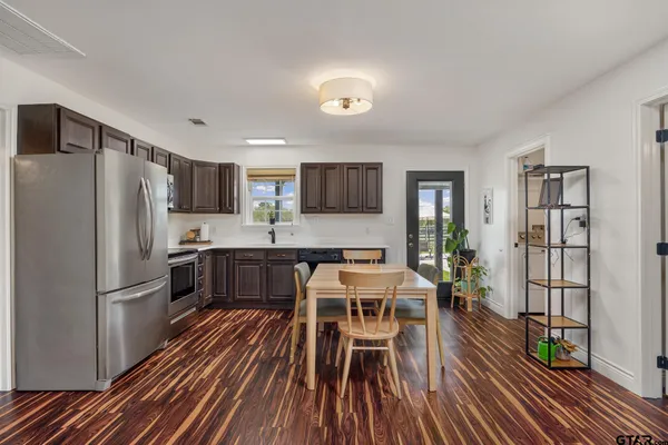a kitchen with stainless steel appliances granite countertop a refrigerator stove microwave and a dining table with wooden floor