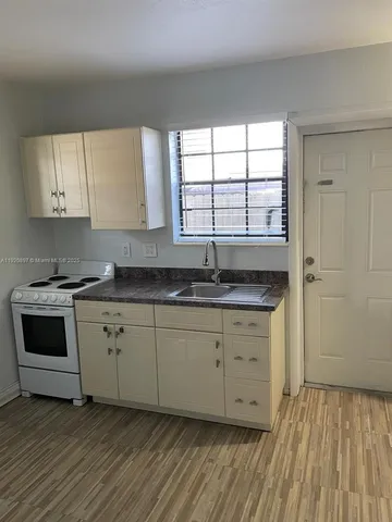 a kitchen with granite countertop white cabinets sink and window