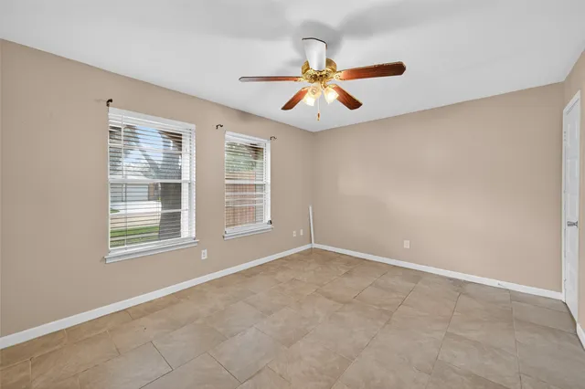 an empty room with windows and fan chandelier fan