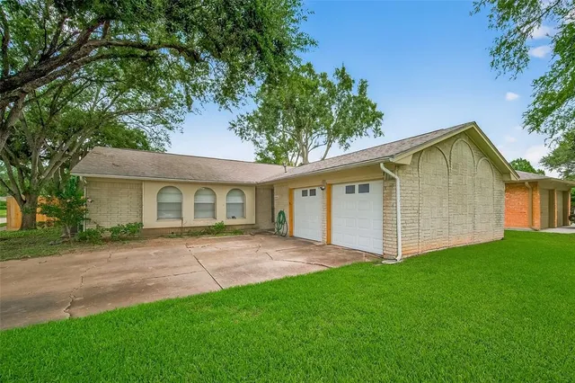 a view of a house with a yard and large tree