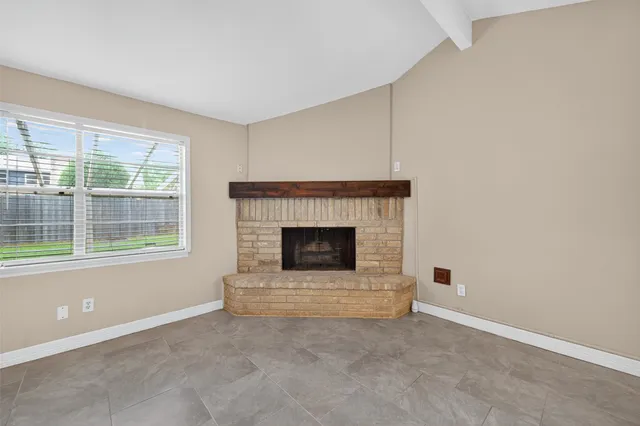 a view of an empty room with a fireplace and a window