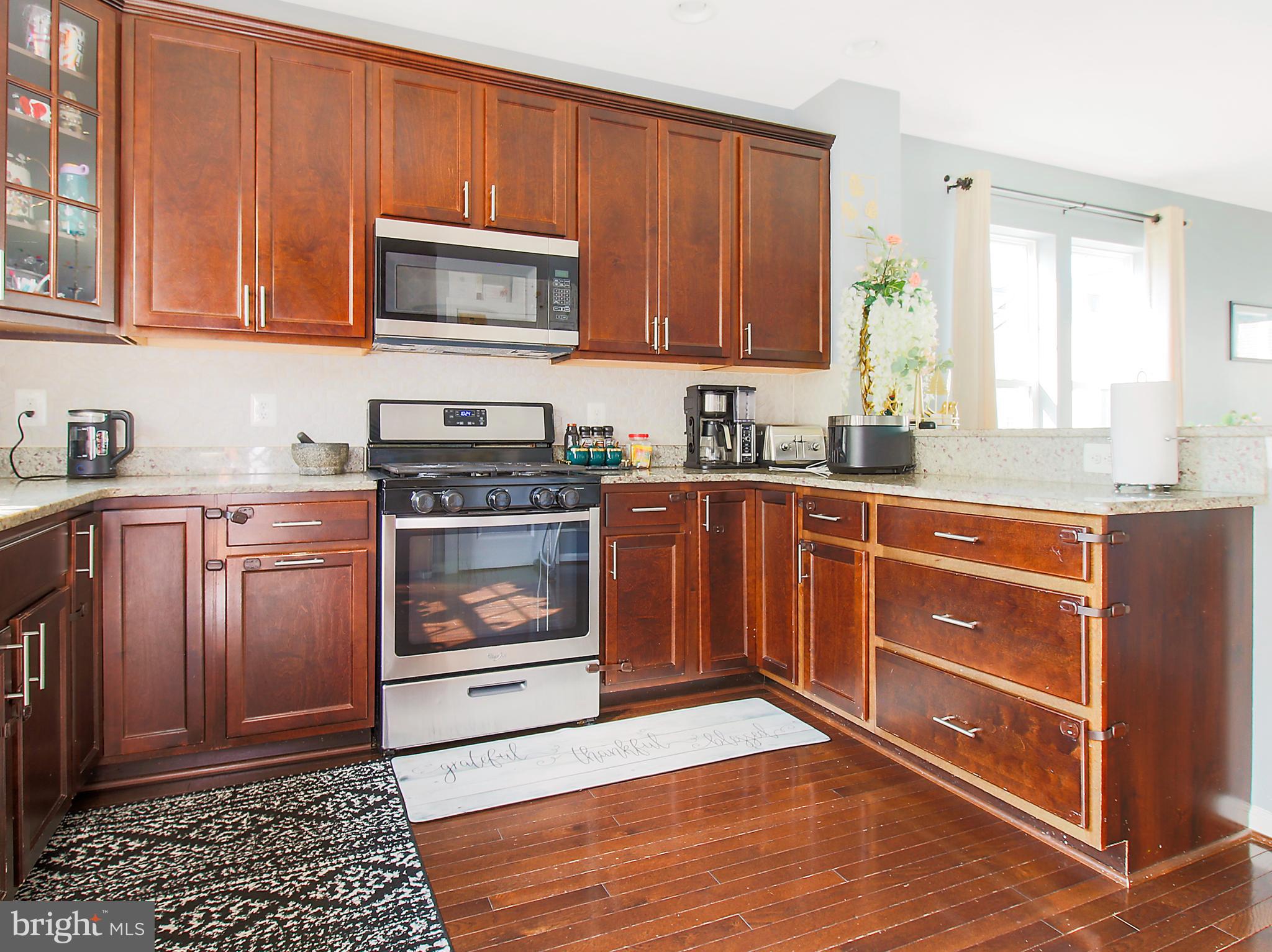 7465 Riding Meadow Way, Unit 42 Manassas, VA 20111 - Photo 14 of 26 a kitchen with stainless steel appliances granite countertop a stove a sink dishwasher and a microwave oven with cabinets