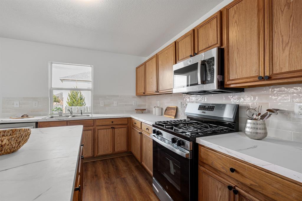 4816 Star Ridge Drive Fort Worth, TX 76133 - Photo 10 of 23 a kitchen with stainless steel appliances granite countertop a stove a sink and a microwave