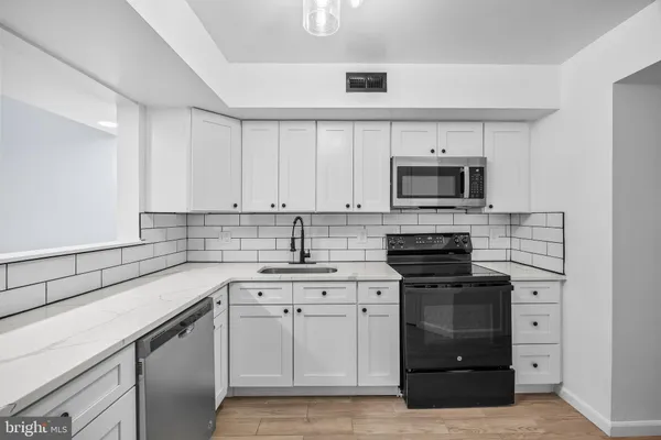 a kitchen with white cabinets sink and stainless steel appliances