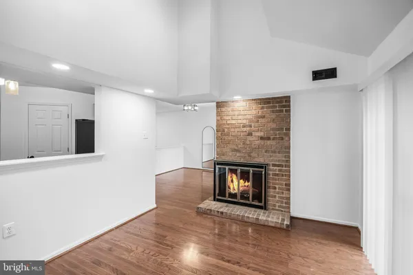 a view of an empty room with wooden floor and a fireplace