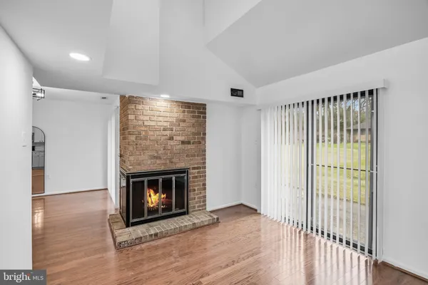 a view of an empty room with wooden floor fireplace and a window