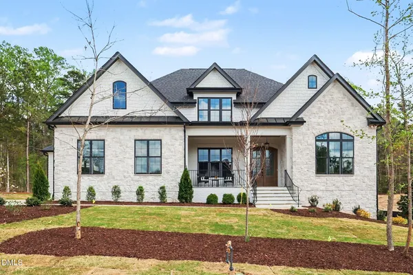a view of a white house with large windows next to a yard