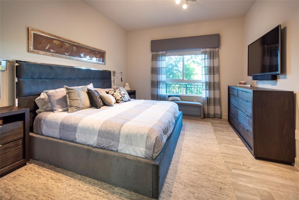 16102 Emerald Estates Drive, Unit 207 Weston, FL 33331 - Photo 13 of 32 a bedroom with a large bed and a flat tv screen on dresser