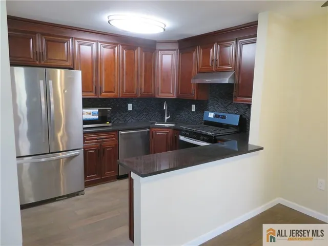 a kitchen with granite countertop a refrigerator stove and sink