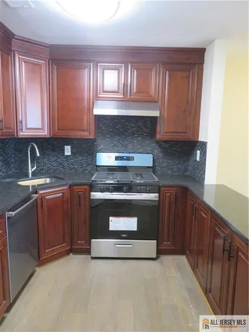 a kitchen with granite countertop a stove sink and cabinets