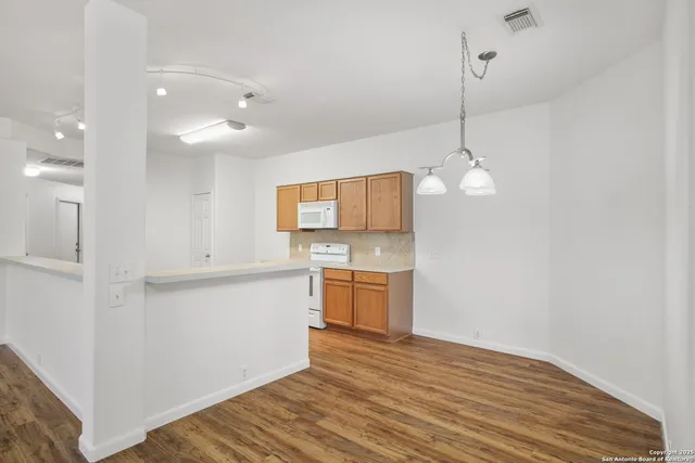 a open kitchen with a sink dishwasher a refrigerator and white cabinets with wooden floor