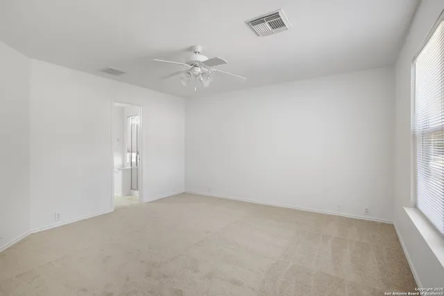 an empty room with a window and ceiling fan
