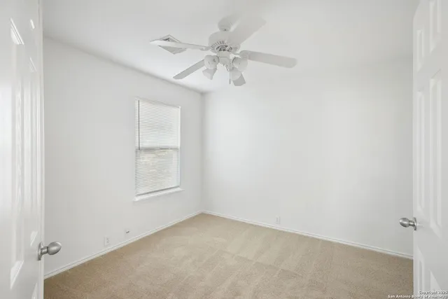 an empty room with a window and a fan