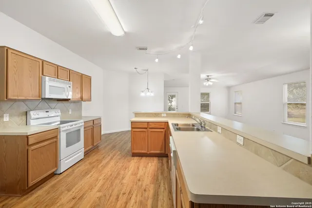 a large kitchen with a lot of counter space and wooden floor
