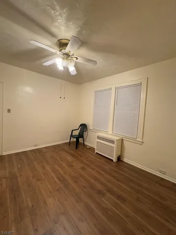 a view of a room with wooden floor and a ceiling fan