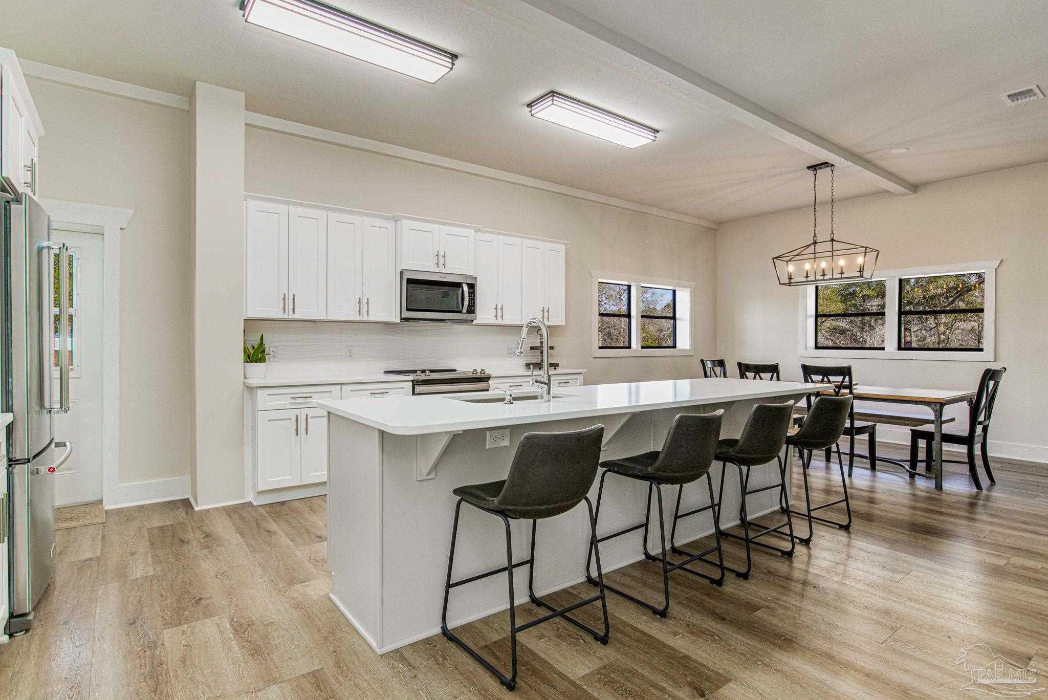 4664 Kolb Road Milton, FL 32570 - Photo 11 of 20 a kitchen with stainless steel appliances granite countertop a stove a sink a refrigerator a microwave oven with white cabinets and wooden floor