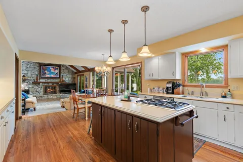 a kitchen with stainless steel appliances granite countertop a sink a stove a refrigerator and island with wooden floor