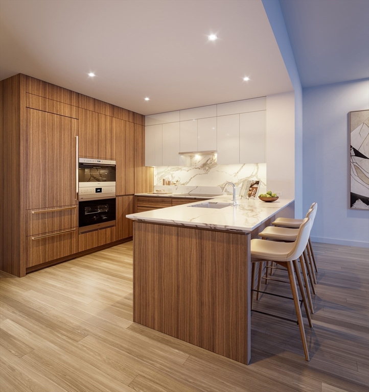 682 Atlantic Avenue, Unit 40G Boston, MA 02111 - Photo 2 of 13 a kitchen with kitchen island a wooden floor and chairs