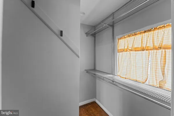 an empty room with wooden floor closet and windows