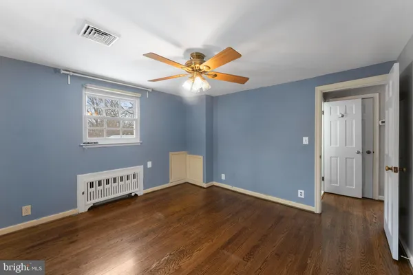 a view of an empty room with window and wooden floor
