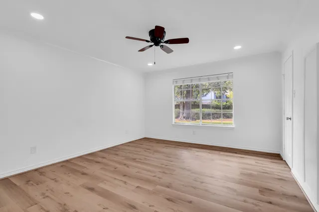 a view of empty room with wooden floor and fan