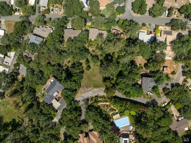 an aerial view of residential houses with outdoor space and trees