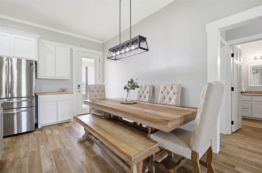 5480 New Hope Road Aubrey, TX 76227 - Photo 11 of 39 a living room with a dining table wooden floor and a chandelier