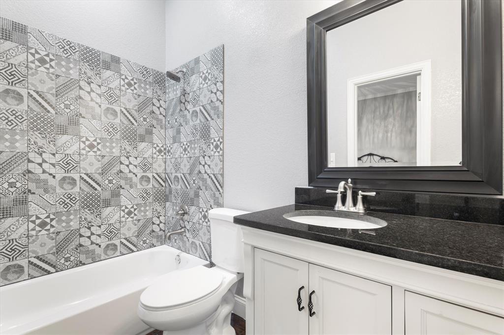 5480 New Hope Road Aubrey, TX 76227 - Photo 19 of 39 a bathroom with a granite countertop sink a toilet and a mirror