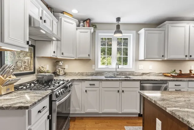 a kitchen with stainless steel appliances granite countertop a sink stove and cabinets