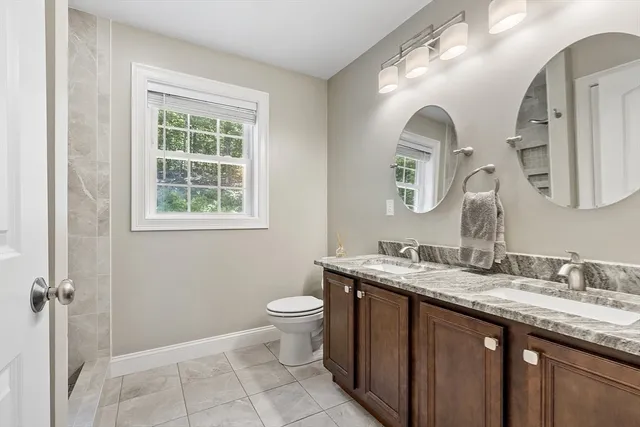 a bathroom with a granite countertop sink mirror and a toilet