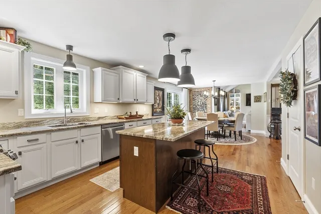 a open kitchen with granite countertop a sink and dishwasher a stove top oven with wooden floor